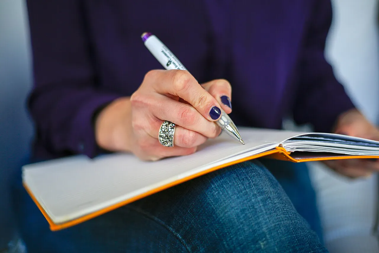 Woman writing on a notebook with a pen